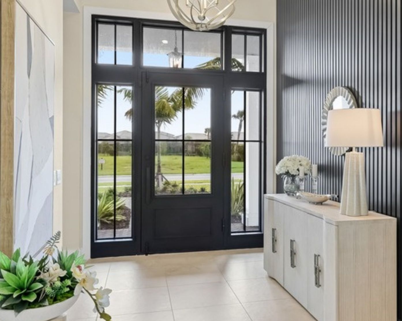 Front entry with a floor-to-ceiling black vertical slat wall beside a pale console and a glass front door